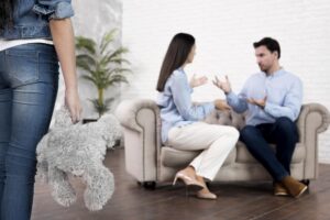 Daughter with teddy bear looking at parents arguing